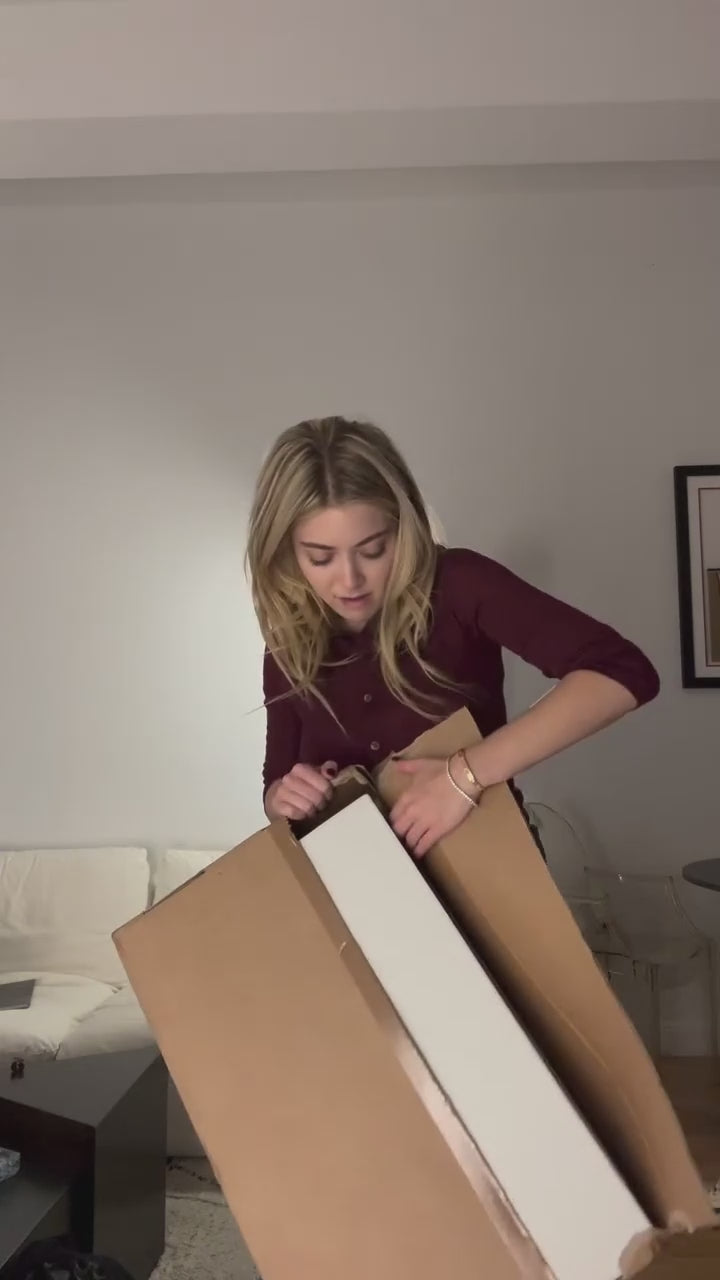 A woman opens an order package from BALTINI, revealing a pair of luxurious black boots. She carefully unboxes the item, showcasing the details and quality of the footwear